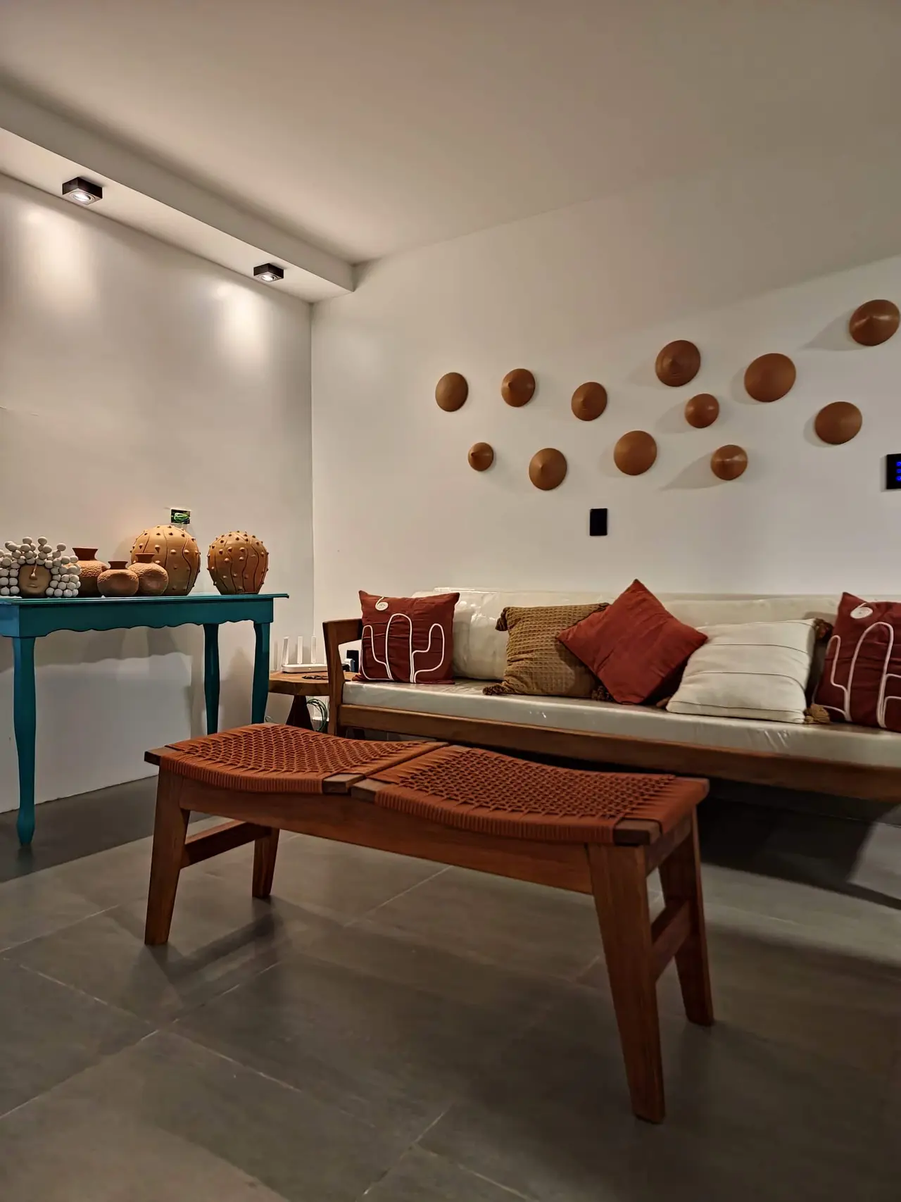 Sala de estar com sofá de almofadas terracota e cerâmicas decorativas na parede