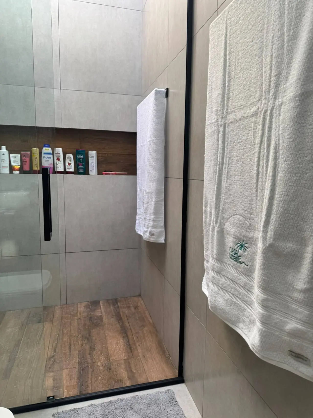 Box do chuveiro com toalha e piso de madeira