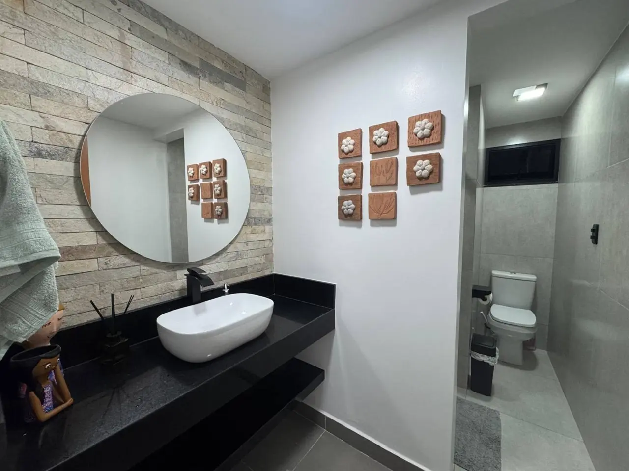 Lavabo com parede de pedra, espelho redondo e cuba branca