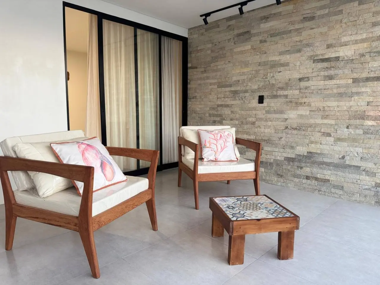 Poltronas com almofadas e mesa de centro junto à parede de pedra