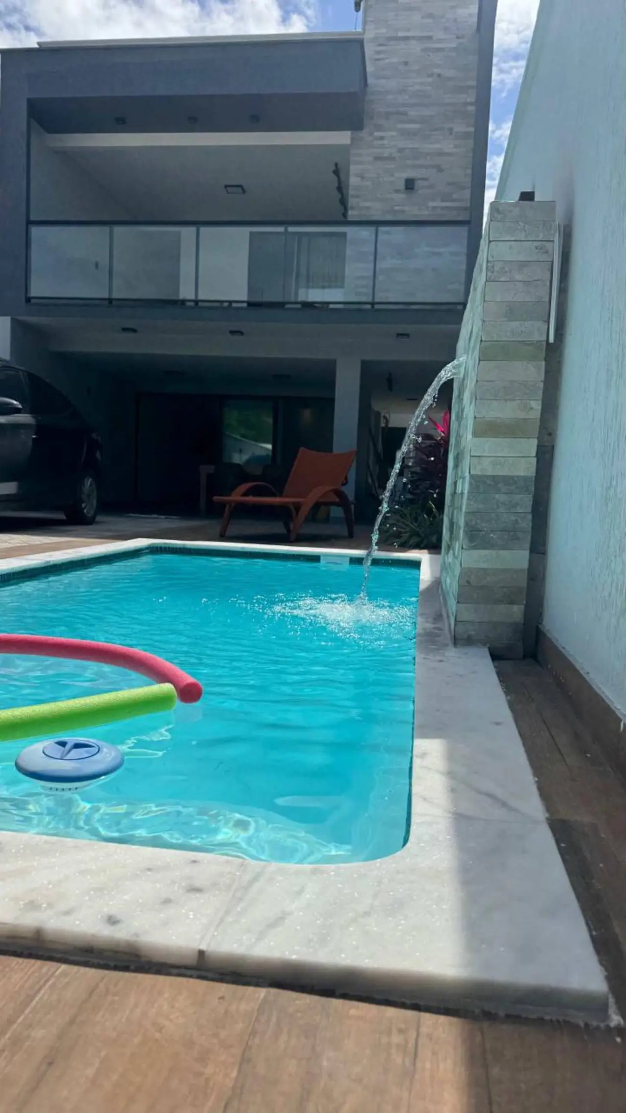 Piscina de dia, de água turquesa, com a cascata caindo ao fundo
