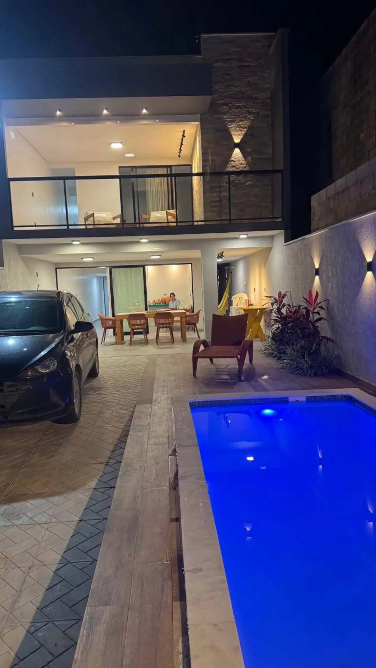 Piscina vista do pátio, com a casa de dois andares ao fundo